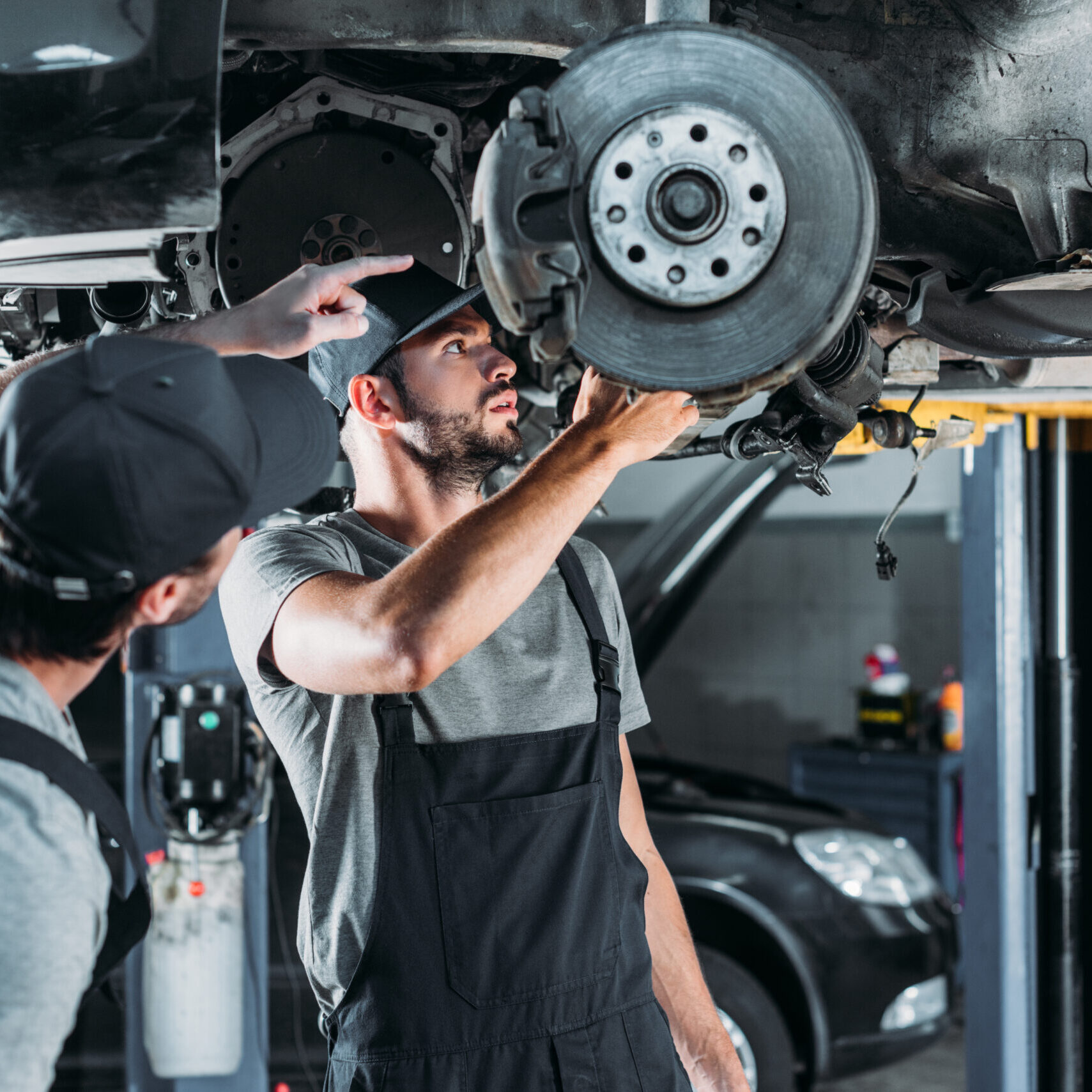 auto mechanics repairing car without wheel in workshop